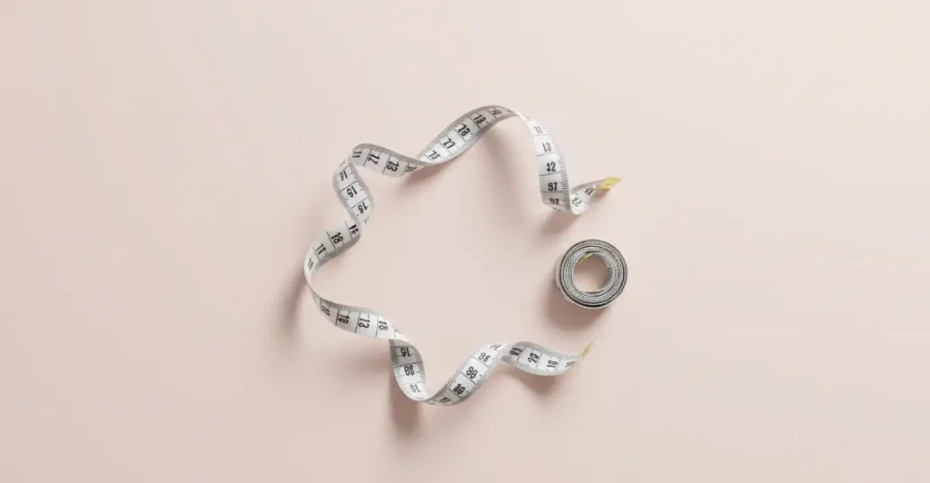 Measuring tape on pink background representing double d breast size measurement guide